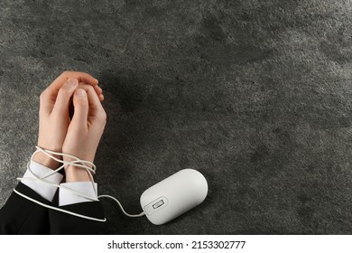 Man showing hands tied with computer mouse cable at grey table, top view and space for text. Internet addiction