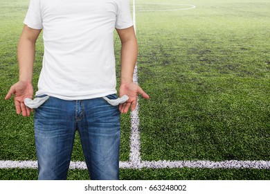 Man showing his empty pockets on soccer stadium background.