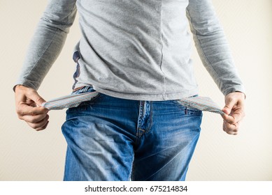 man showing his empty pockets over light background. Concept of crisis, moneyless, bankrupt, unemployment, poverty, credit, economy and jobless