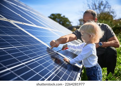 Man showing his small child the solar panels during sunny day. Father presenting to son modern energy resource. Little steps to alternative energy.