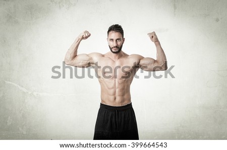 man showing muscles in abstract room. textured wall