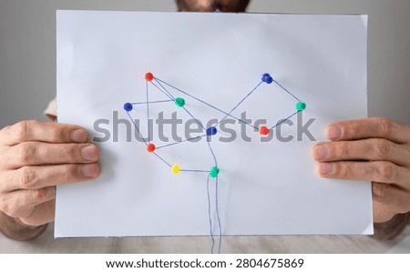 Man showing network connection with a push pins and thread.