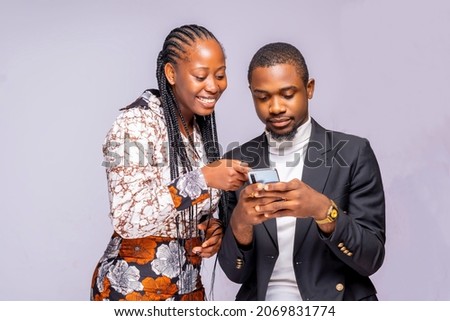 man showing woman his phone.Image of joyful black African couple 20s smiling and looking at mobile phone isolated over white studio background