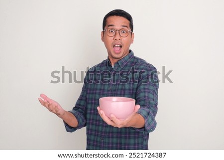 A man showing wow face while holding empty dinning bowl