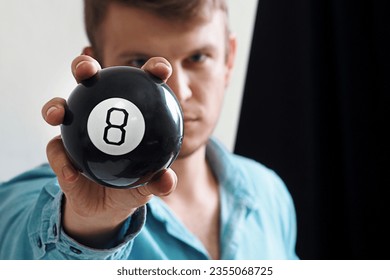 Man shows ball with number to camera. Lucky number or winning lottery. Numerology and divination. Number eight on round ball. - Shutterstock ID 2355068725