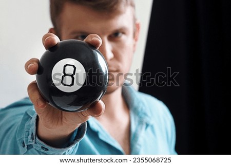 Man shows ball with number to camera. Lucky number or winning lottery. Numerology and divination. Number eight on round ball.