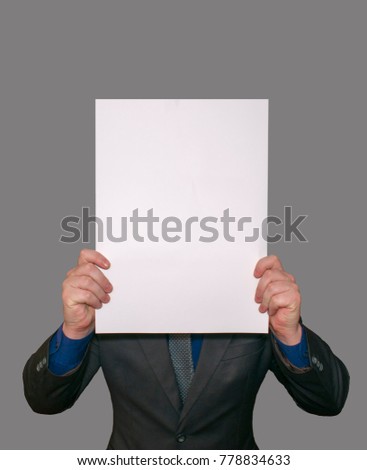 A man shows an empty white large A3 A2 paper, covering his face. Presentation of leaflets. Leaf pattern. The face of the sheet is read. Template for writing on a sheet
