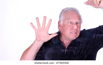 A Man Shows His Sense Of Humor As He Presses His Face Against A Glass Window Making The Impression Of A Dead Bug On A Windshield Of A Car. Isolated On White. Model Released. Focus In Front Of Glass.