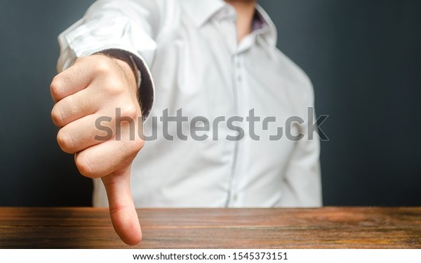 A man shows a thumb down. Gesture of\
disapproval and rejection. Bad assessment, harsh criticism, failure\
and defeat. Refusal to pass and cooperation. Bureaucratic\
obstacles. Contempt and\
condemnation