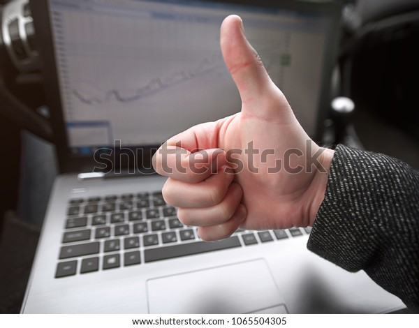 man shows thumbs up on laptop background with graph of\
sales growth\
business man working while being in the car.\
\
