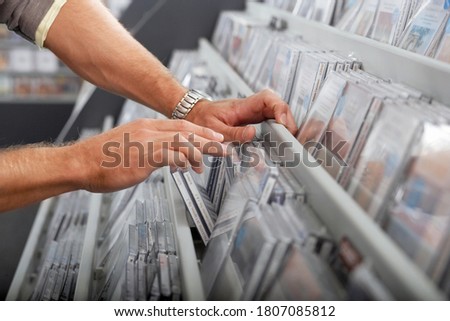 Man sifting through CDs in record shop, side view, mid-section, close-up