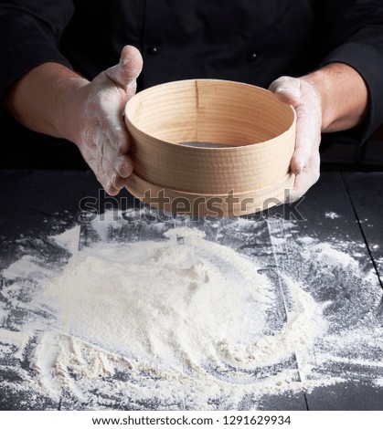 Image, Stock Photo man sifts white wheat flour through a wooden sieve