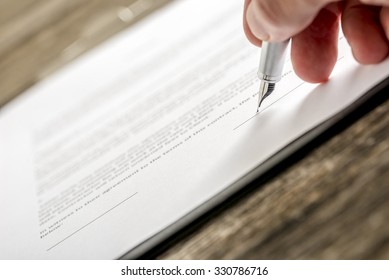 Man signing business document, application, subscription form  or insurance papers with silver pen on wooden desk. - Shutterstock ID 330786716