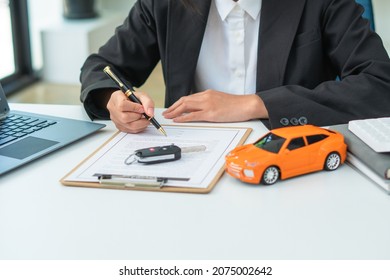 Man signing car insurance document or lease paper. Writing signature on contract or agreement. Buying or selling new or used vehicle. Car keys on table. Warranty or guarantee. Customer or salesman. - Shutterstock ID 2075002642