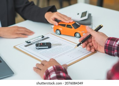 Man signing car insurance document or lease paper. Writing signature on contract or agreement. Buying or selling new or used vehicle. Car keys on table. Warranty or guarantee. Customer or salesman. - Shutterstock ID 2076084349