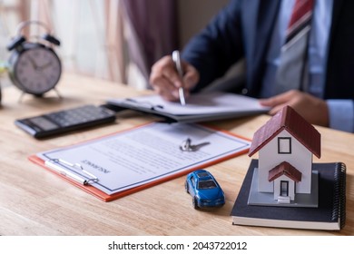 Man signing a contract when buying a new house and car Purchase agreement for ours with model home, Man sign a home insurance policy on home loans, Businessman signing contract insurance