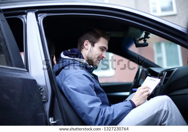 man signs a\
document while sitting in the\
car