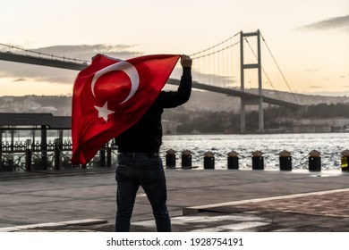 Man silhouette hold Turkish Flag in front of 15th July Martyrs Bridge (in Turkish 15 Temmuz Sehitler Koprusu ) or Bosphorus Bridge in Istanbul, Turkey. Patriotism concept.