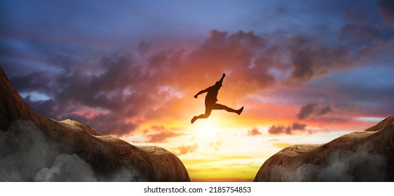 Man of silhouette jumping  over the cliff on sunset background, Freedom of life or business concept idea - Powered by Shutterstock