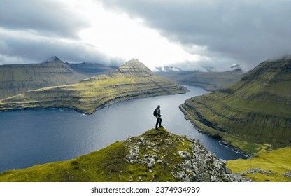 Man silhouette on background Funningur fjord from the Funningur top. Eysturoy Island, Faroe islands. Tourist explores natural attractions