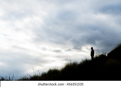 Man In Silhouette On Hill With Cloudy Sky Background