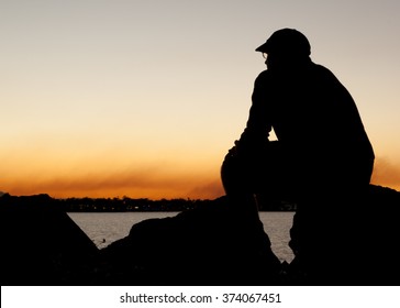 Man in silhouette sitting contemplating watching sunset - Powered by Shutterstock