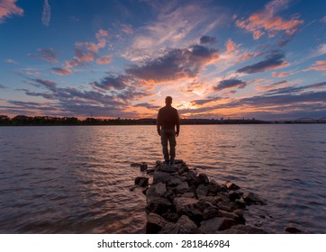 Man silhouette, standing on river stones gangway and contemplating a beautiful sunset. - Powered by Shutterstock