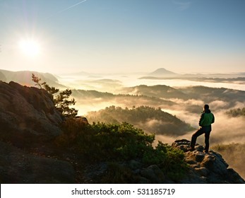 Man silhouette stay on sharp rock peak. Satisfy hiker enjoy view. Tall man on rocky cliff watching down to landscape. Vivid and strong vignetting effect. - Powered by Shutterstock