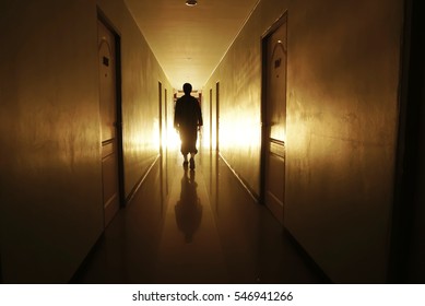 Man Silhouette Walking Through A Lit Corridor, Which Conveys The Concepts Of Rebirth,evolution And Achievement