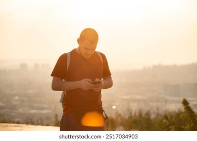 Man silhouetted against dawn sky, modern technology meets timeless urban landscape. Solitary hiker checks phone atop misty urban overlook - Powered by Shutterstock