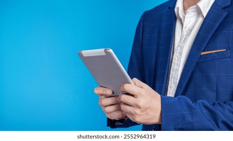 A man in a silver suit is celebrating success by holding a green screen phone against a blue background, representing happiness and success. - Powered by Shutterstock