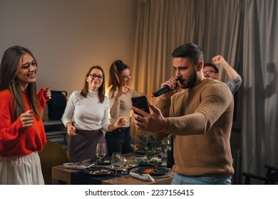 Man is singing in the microphone at a home karaoke party - Powered by Shutterstock