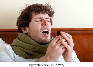 Man With Sinus Infection Sneezing In Bed