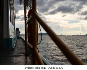 A man sit down on front of local boat and looking scenery.