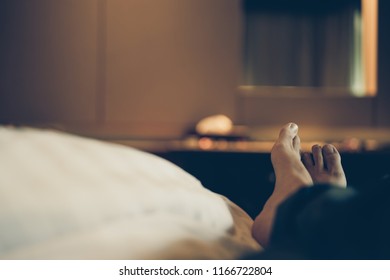 Man Sit On Hotel Bed, Focus On Feet, Vacation Concept