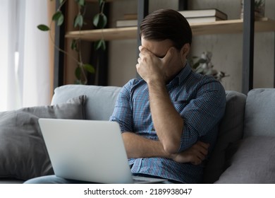 Man Sit On Sofa With Laptop Cover Face With Hand Got Bad News Feels Disappointed, Looks Distressed With Awful E-mail, Having Problems, Miss Appointment, Confused By Mistake Or Error, Troubles