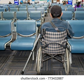 Man Sit On Wheelchair With Staff Using Smart Phone And Waiting In Airport, Portrait Of Man Wearing Casual Style Clothes Sitting On Wheelchair In Modern Airport Using Smartphone. Passenger Travelling 