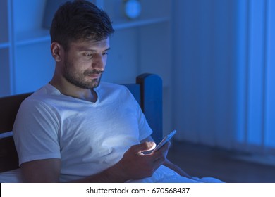 The Man Sit With A Phone In The Bed. Night Time