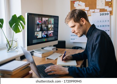 Man sitzt auf dem Desktop-Computer und macht Notizen. Fernbediente junge Mann, die Videoanrufe über Computer im Heimbüro führen. Bleiben Sie zu Hause und arbeiten Sie von zu Hause aus. Management-Team-Sitzung