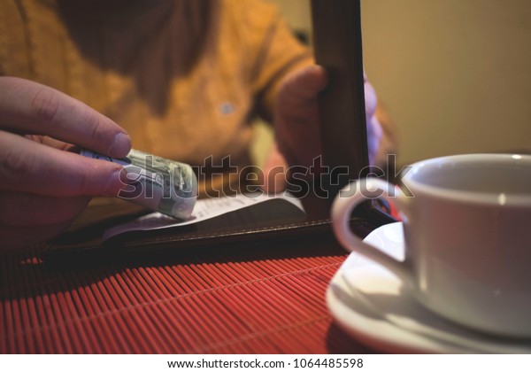 a man sits in a\
cafe, pays cash in a cafe