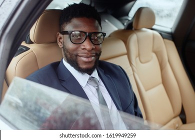 Man sits in a car and looks at the camera smiling.