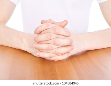 Man sits at a desk with his hands clasped showing power and confidence.