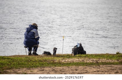 A man sits on a bench by the water, fishing with a dog by his side. The scene is peaceful and serene, with the man and his dog enjoying the outdoors - Powered by Shutterstock