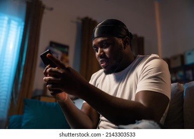 Man Sits On Couch At Night With Phone In Hand, Young Guy With Dark Skin Hacks Websites, Social Networks, Logs Into Bank Website, Forgot Password, Failed Attempt