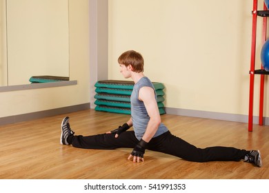 Man sits on a forward split. Stretching after exercise. Healthy lifestyle concept. Fitness.