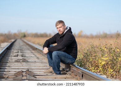 A Man Sits On Rails. Travel By Rail. Man Sits On Rails, Travel On Foot.