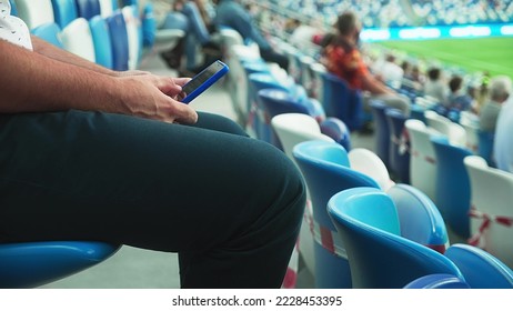 A man sits on the stadium stand and surfing social media on his smart phone during a football or soccer match. Mass event during coronavirus quarantine. Close-up of hands. High quality 4k footage - Powered by Shutterstock