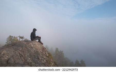 A Man Sits On Top Of A Granite Mountain. Atmospheric Hazy View