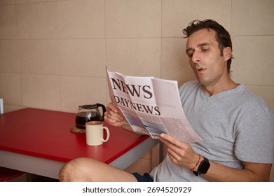 A man sits at a red table reading a newspaper, with a coffee mug and a pot nearby. Relaxed, focused moment captured in a home setting.