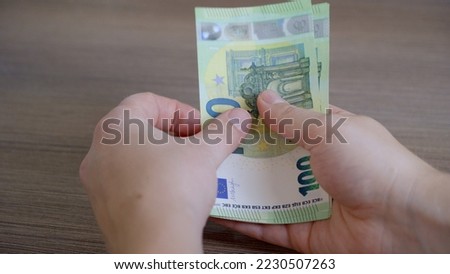 A man sits at a table and counts paper banknotes of one hundred euros, which he will have to pay for utilities that have skyrocketed due to the economic crisis in the country